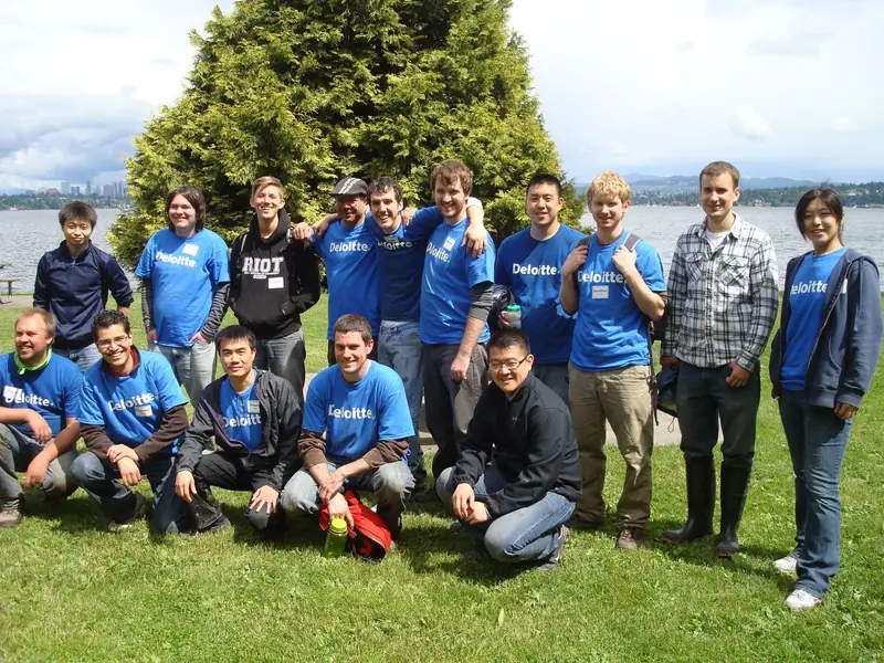 A large group of Deloitte volunteers posing by the lake